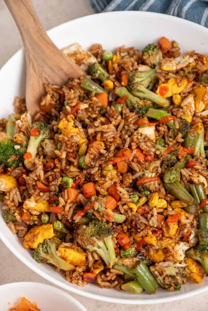 A large white bowl filled with frozen veggie fried rice drizzled with sriracha.
