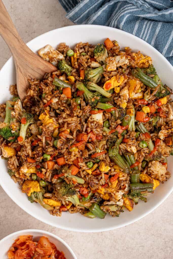 A large white bowl filled with frozen veggie fried rice drizzled with sriracha.