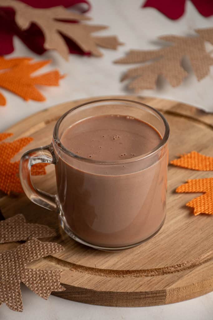A clear glass mug with pumpkin hot chocolate.
