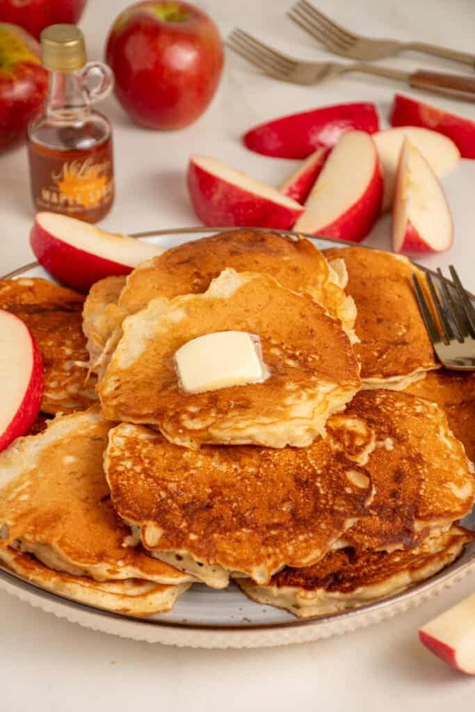 A stack of apple pancakes with a slab of butter on top.